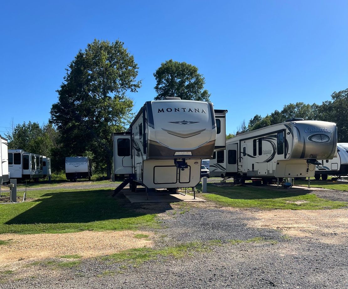 A montana trailer is parked in a gravel lot
