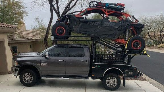 A truck with two atvs on top of it is parked in a driveway.