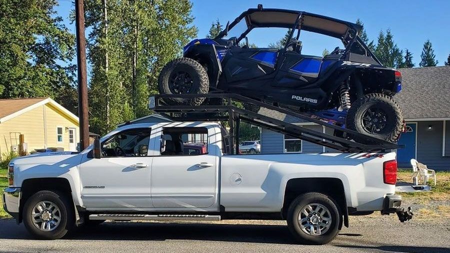 A white truck with two atvs on top of it.