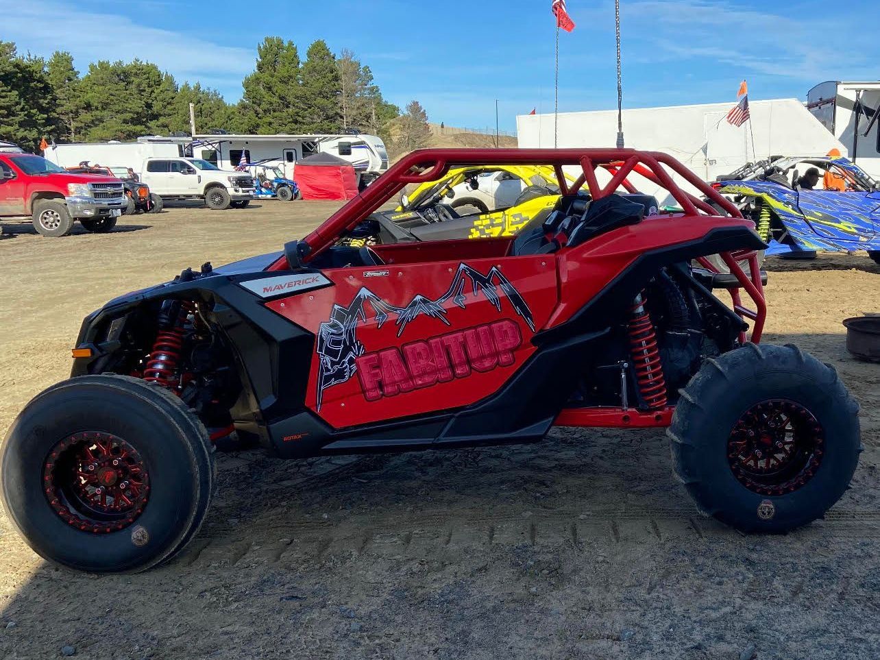 A red and black atv is parked in a dirt field.
