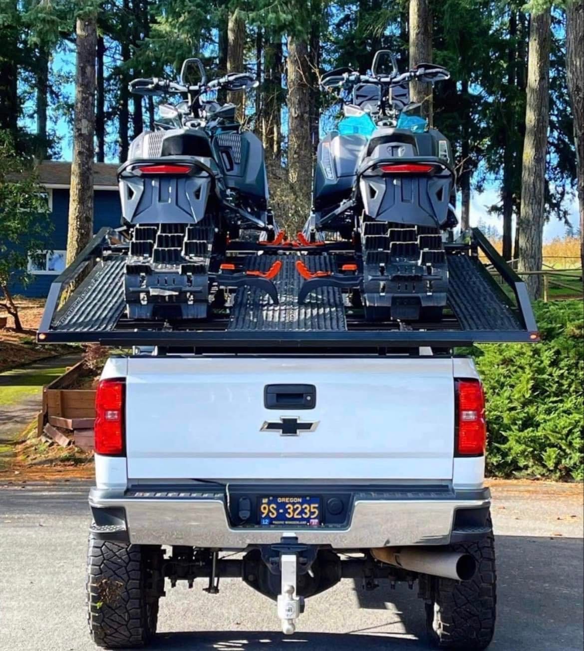 A truck with two motorcycles on the back has a license plate that says 95-2375