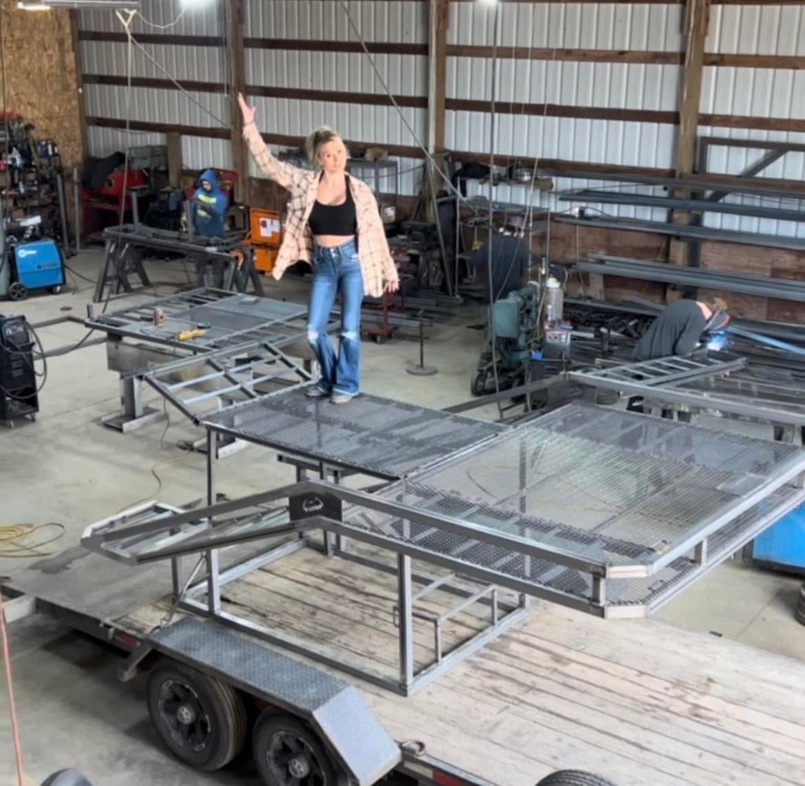 A woman is standing on top of a trailer in a garage.