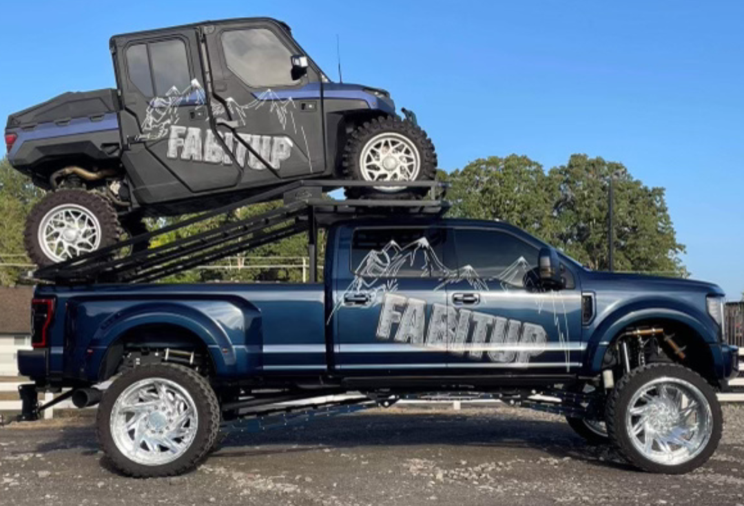 A blue truck with a four wheeler on top of it.