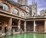 Stone courtyard with arched walkways and a green reflecting pool in a historic building complex