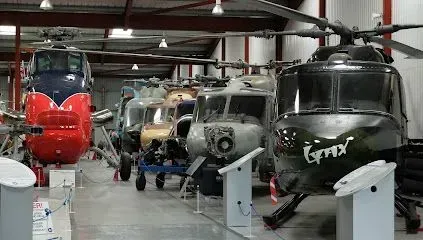 Helicopters on display inside a hangar; various colors and models.