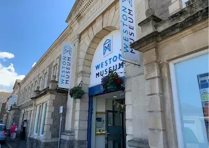 Weston Museum exterior with blue banners, stone facade, sunny day.