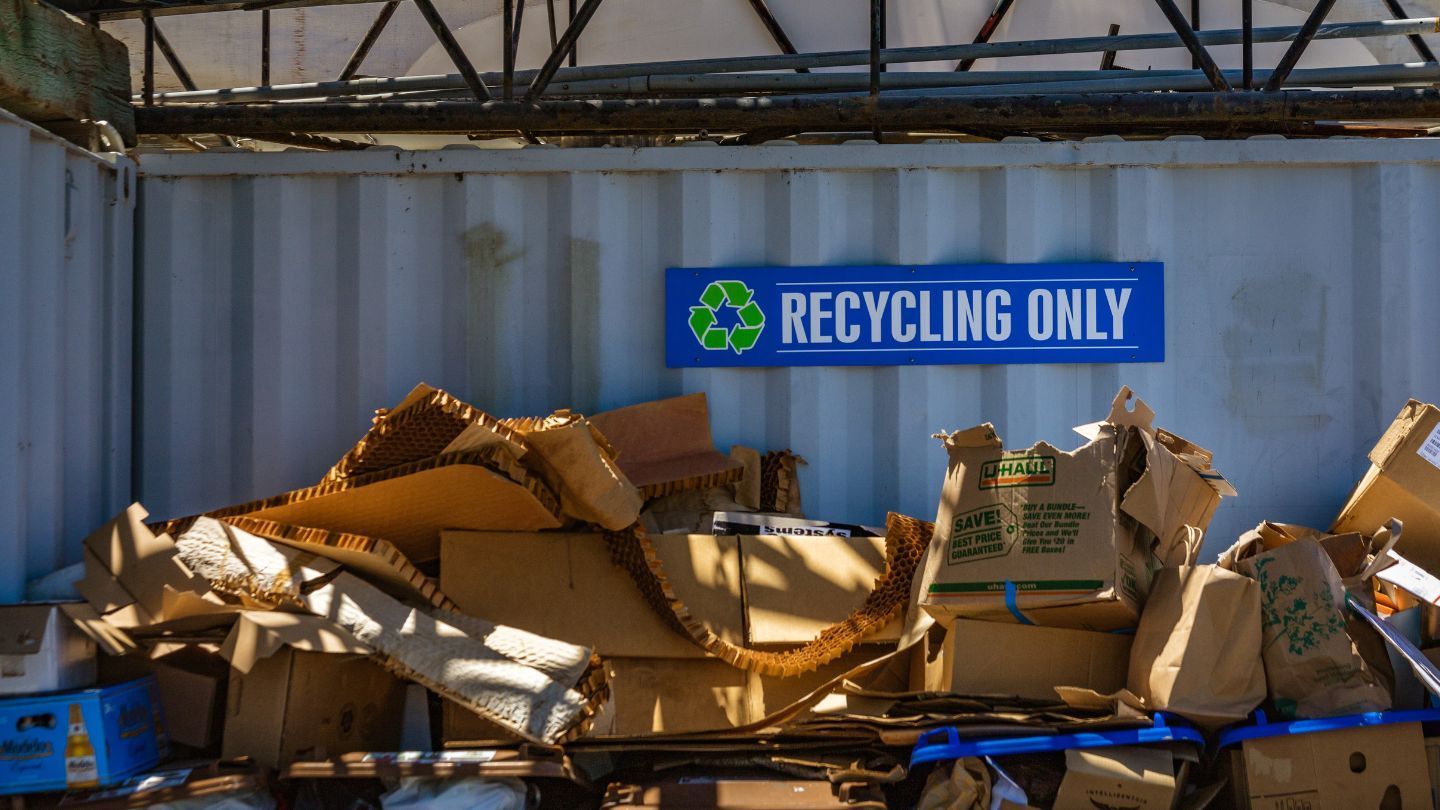 Cardboard boxes piled in a recycling area beneath a 
