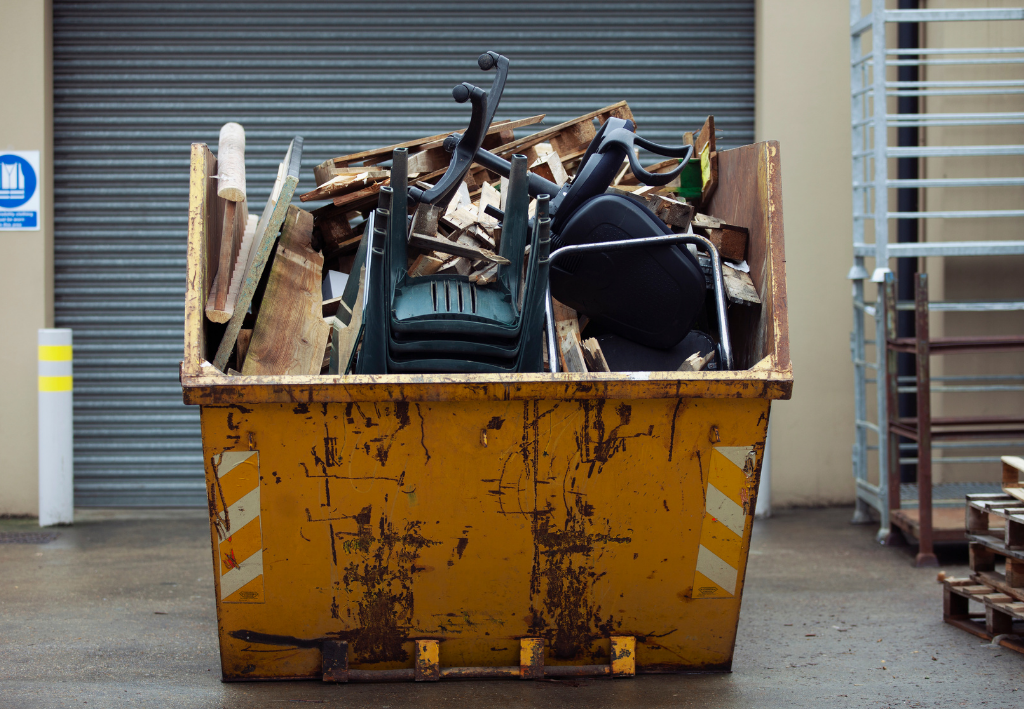 Large yellow dumpster filled with scrap metal and debris in an industrial loading area