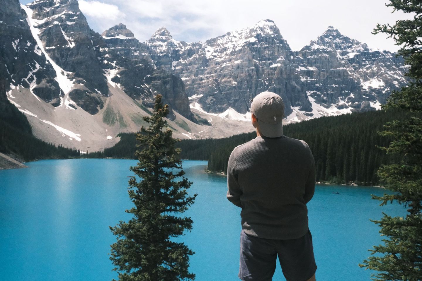 Solo traveller at Moraine Lake Rockpile with Valley of the Ten Peaks covered in late summer snow, Banff Bear Travel