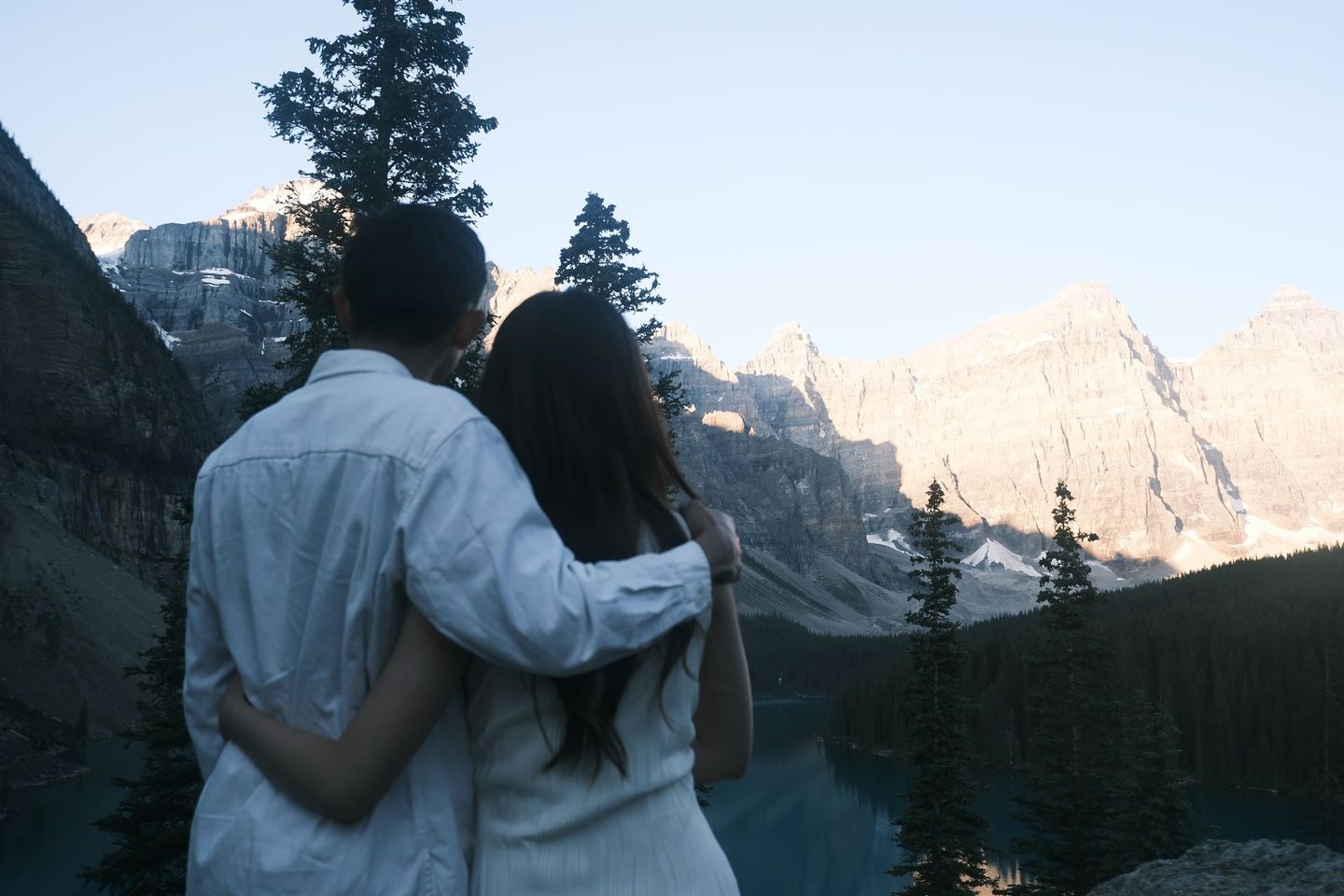 Couple at Moraine Lake during golden hour with Valley of the Ten Peaks glowing in warm light, Banff Bear Travel