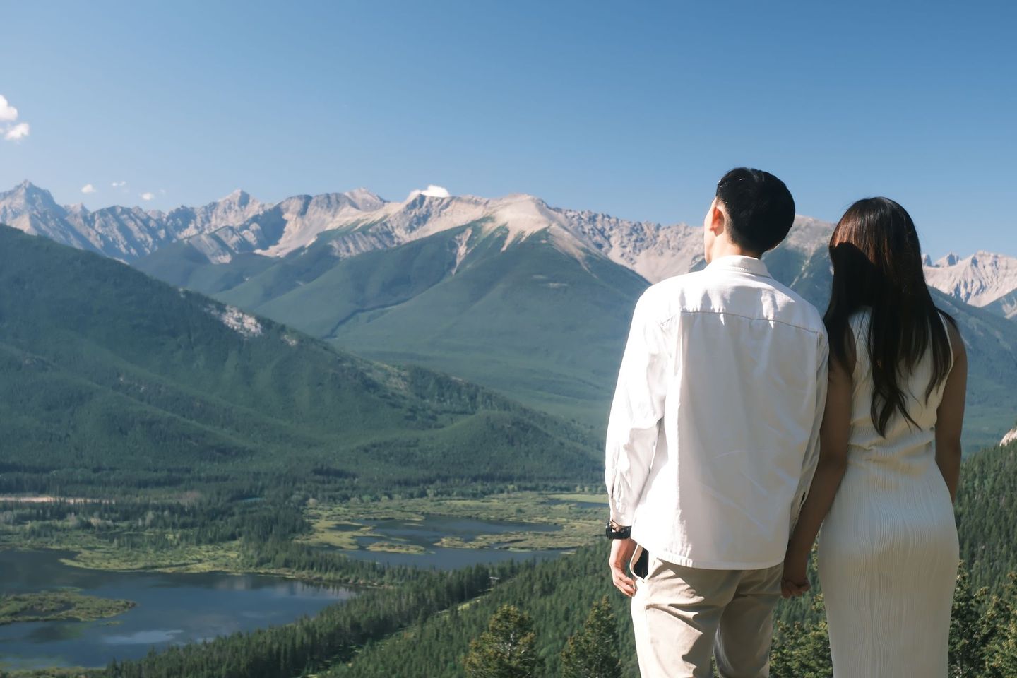 Couple overlooking Banff wetlands and Fairholme Mountain Range from scenic viewpoint, Banff Bear Travel slow travel tour 