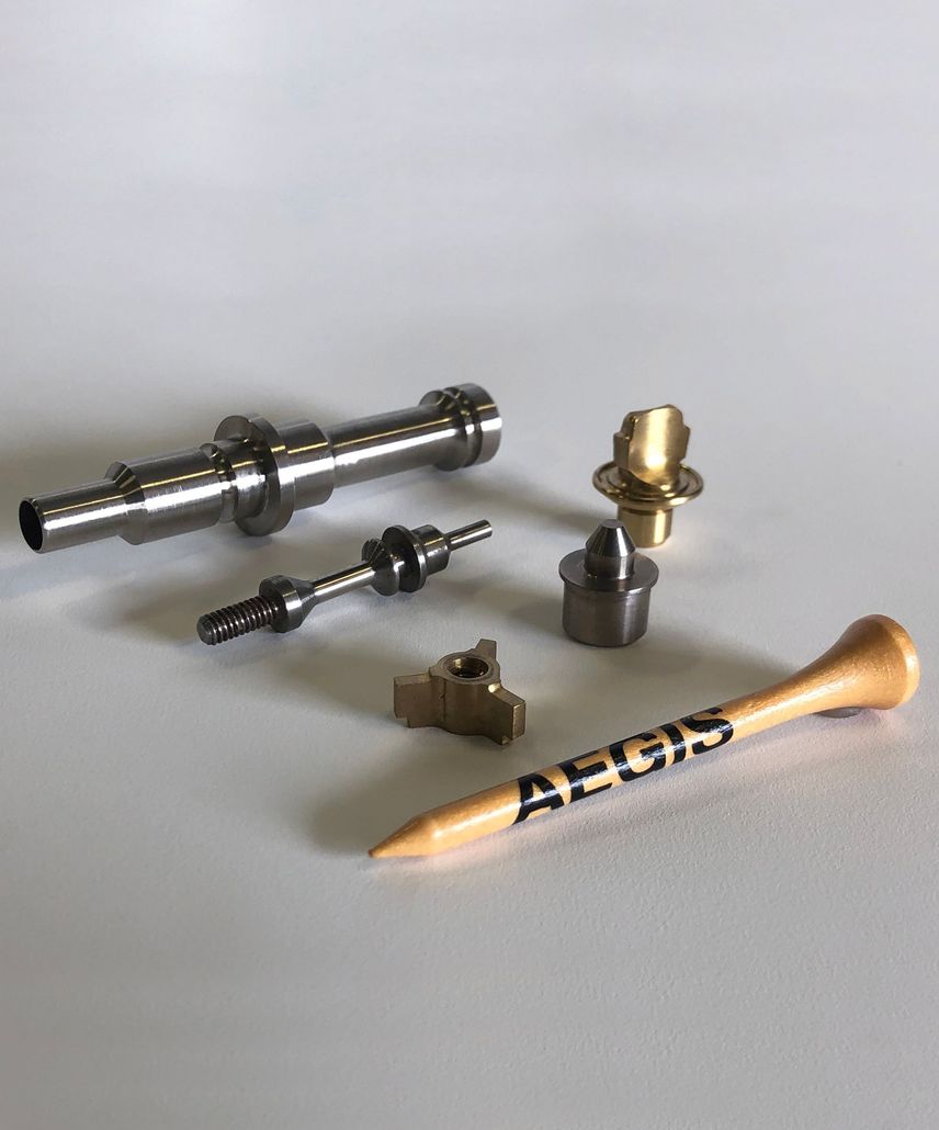 A group of metal parts and a wooden tee are sitting on a table.