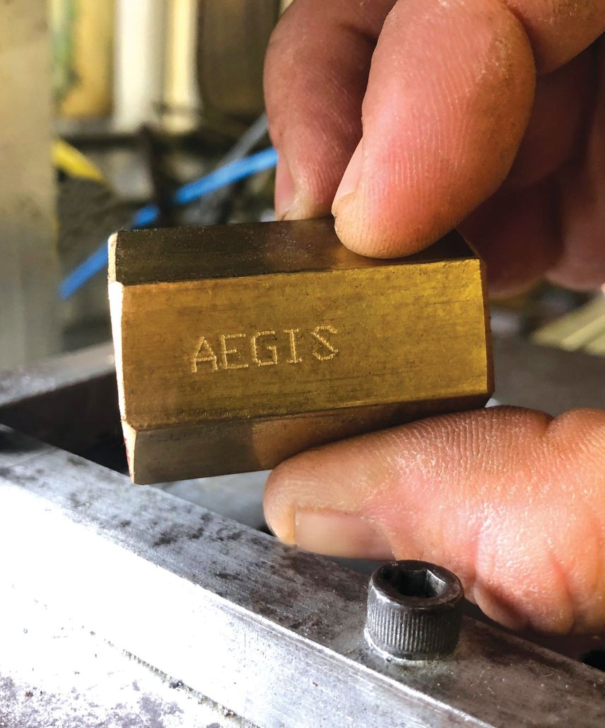 A person is holding a piece of metal that says aegis on it