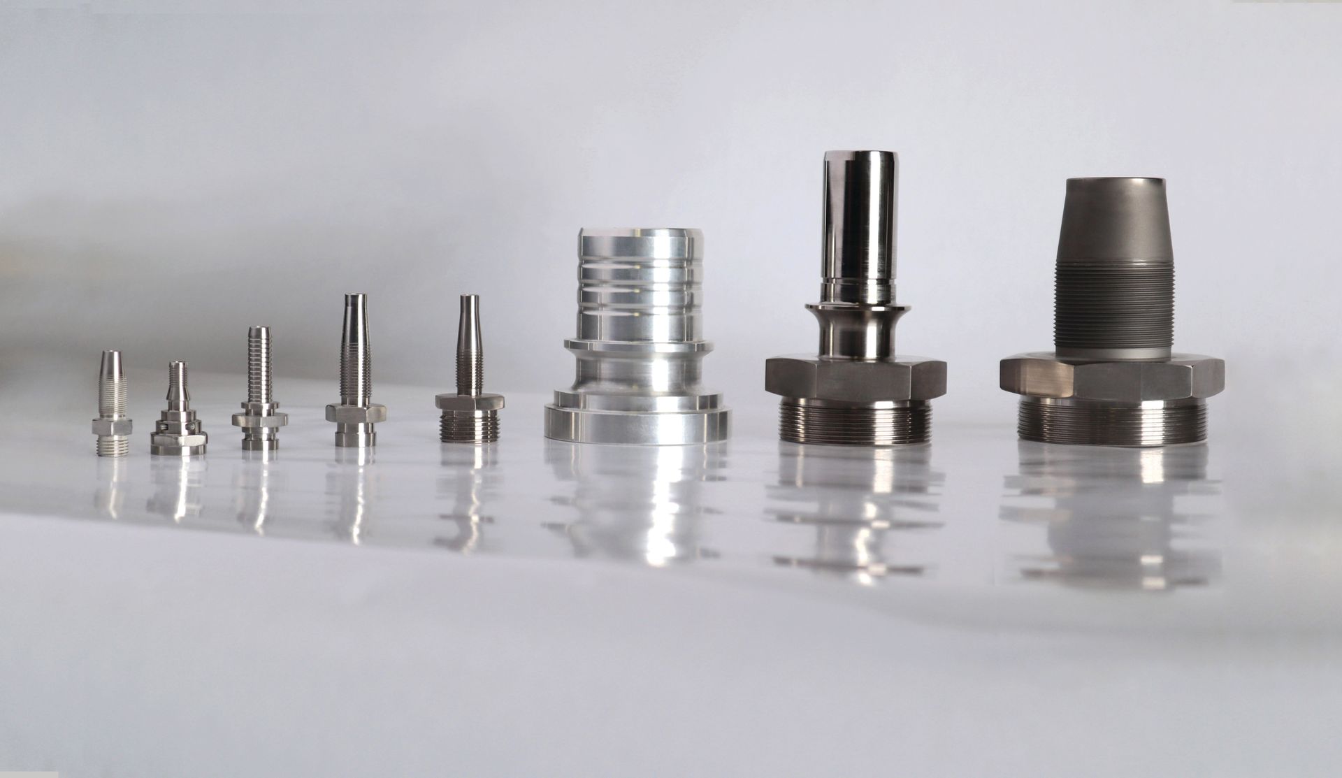 A row of stainless steel fittings are lined up on a table