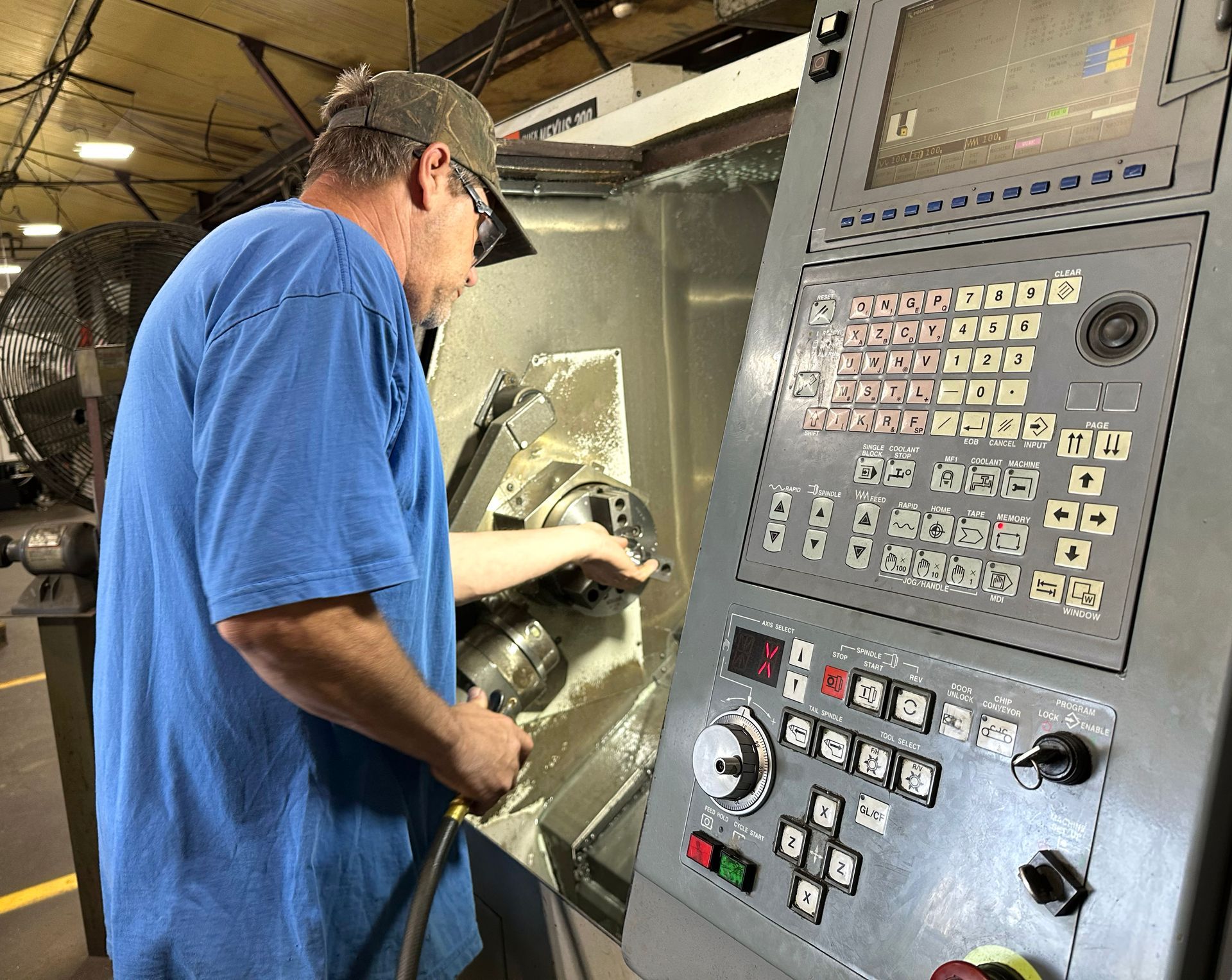 A man in a blue shirt is working on a machine in a factory.