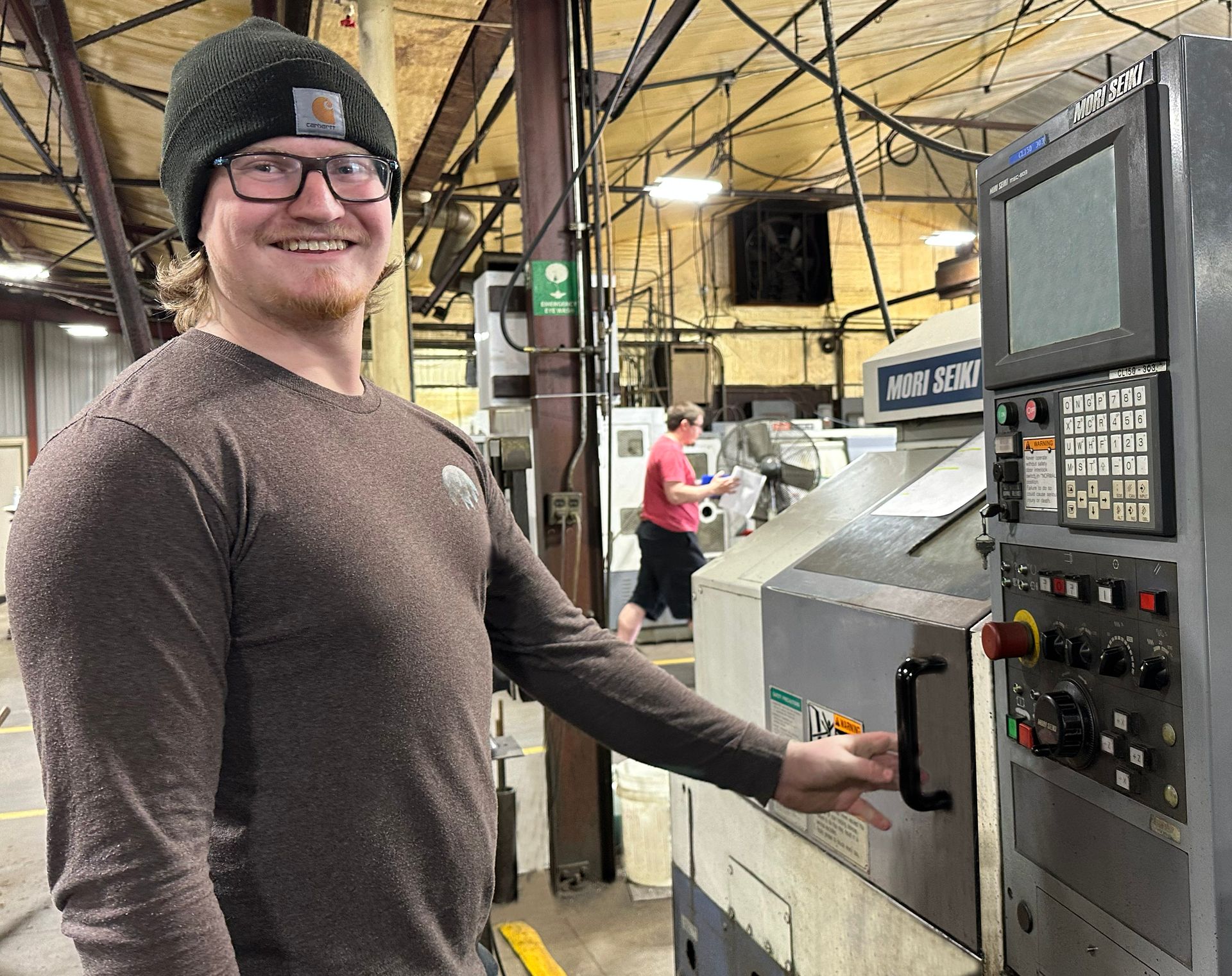 A man is standing in front of a machine in a factory.
