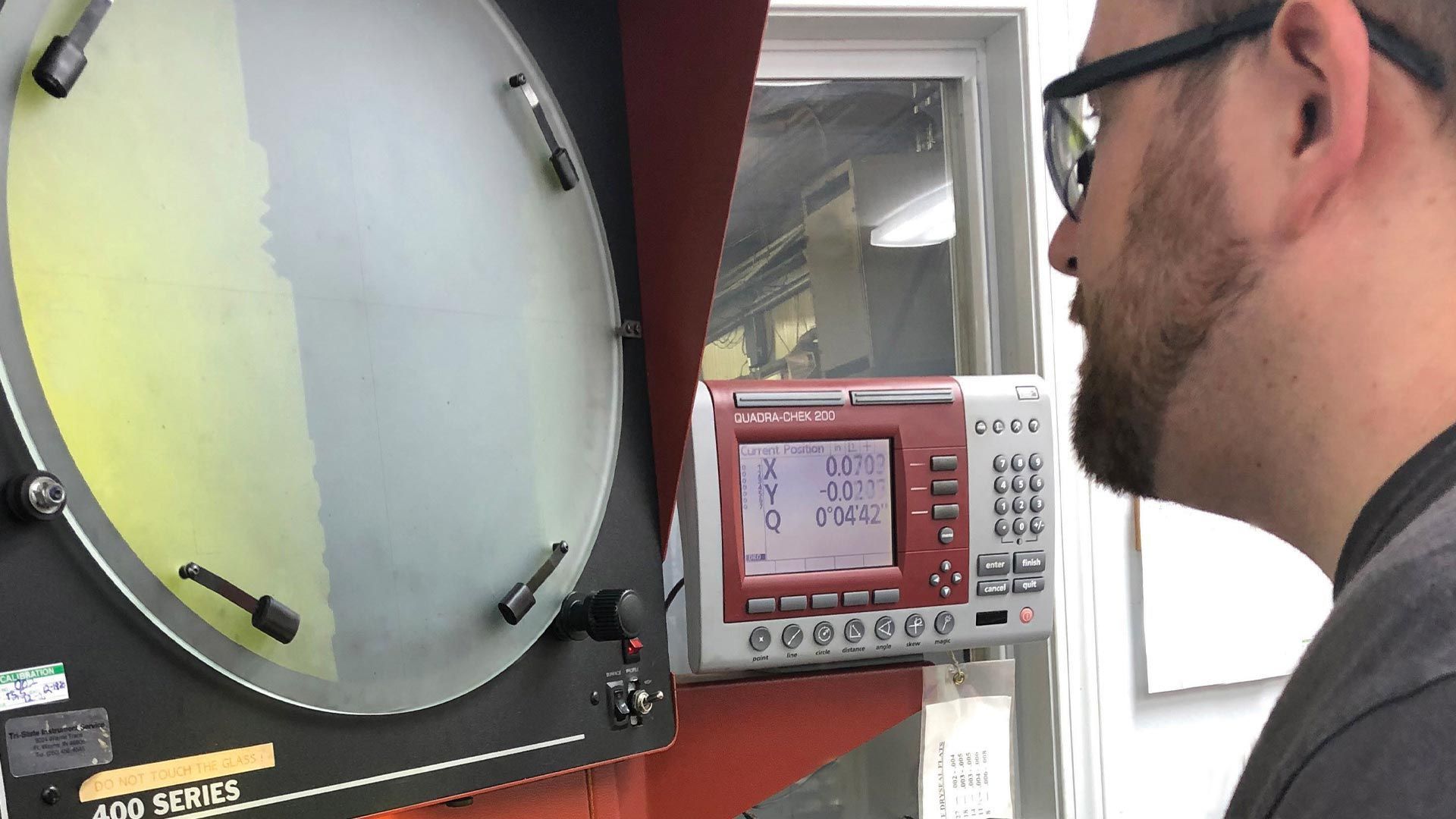 A man wearing glasses is looking at a machine with a clock on it