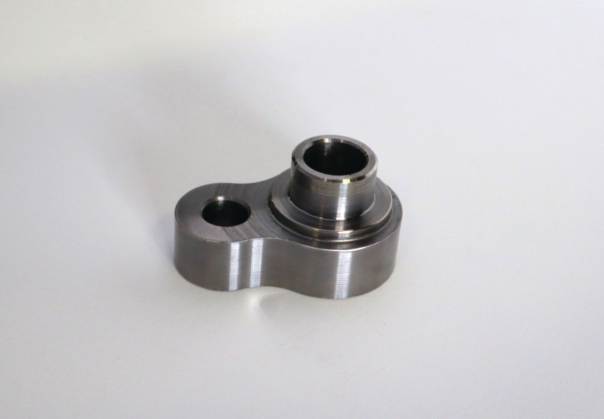 A small metal piece with a hole in the middle is sitting on a white surface.