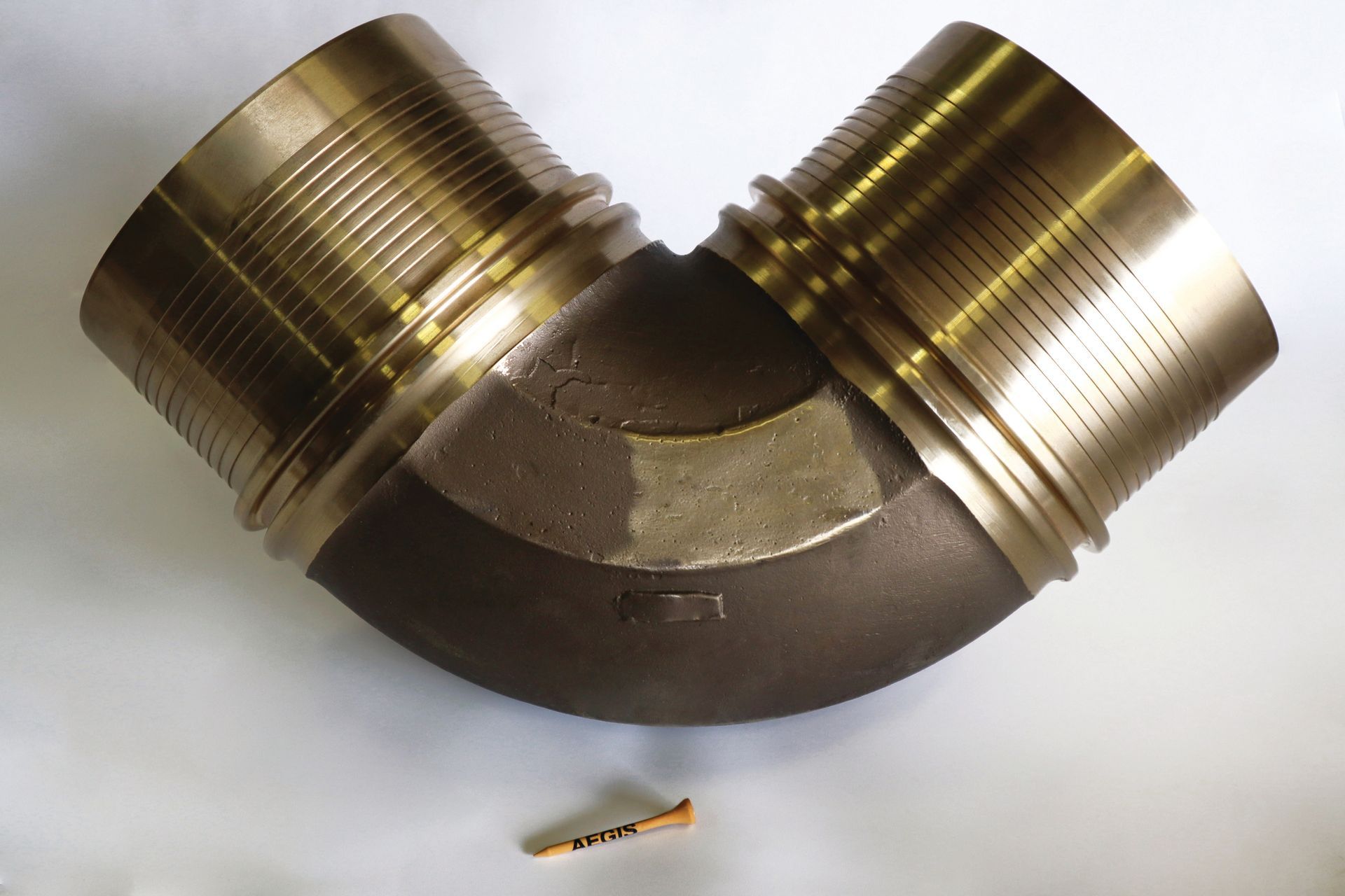 A close up of a brass elbow on a white surface