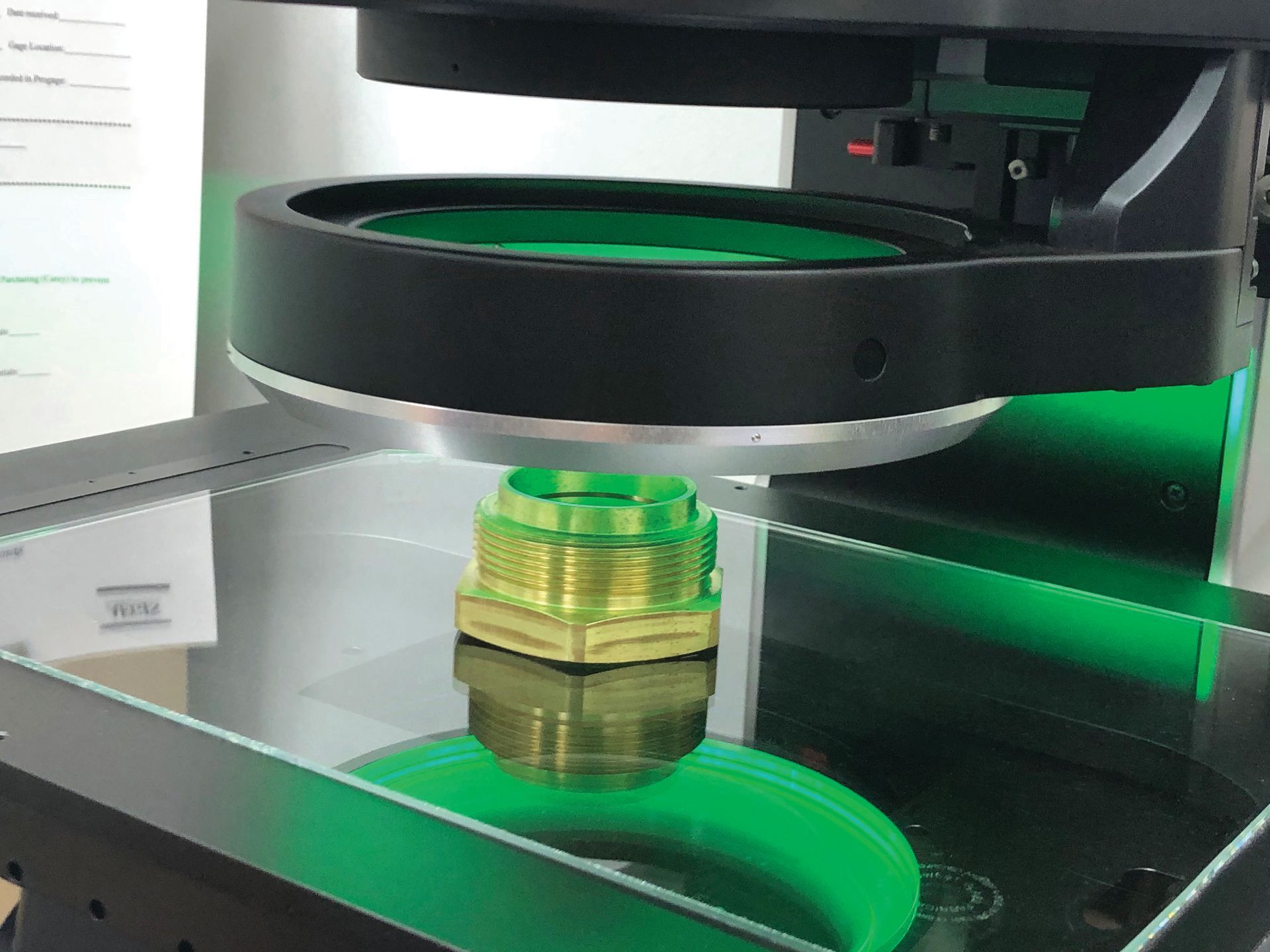 A green object is being printed on a machine