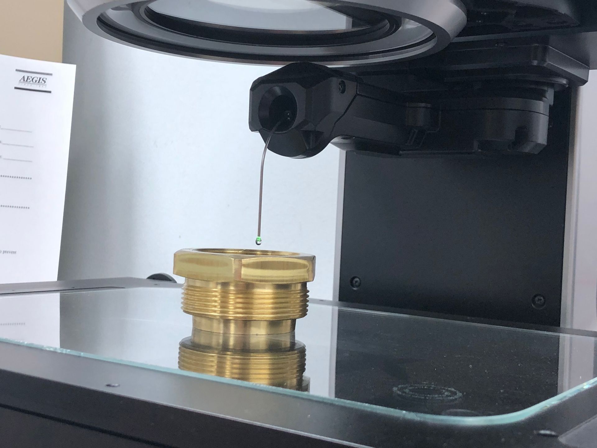 A piece of metal is being examined under a magnifying glass