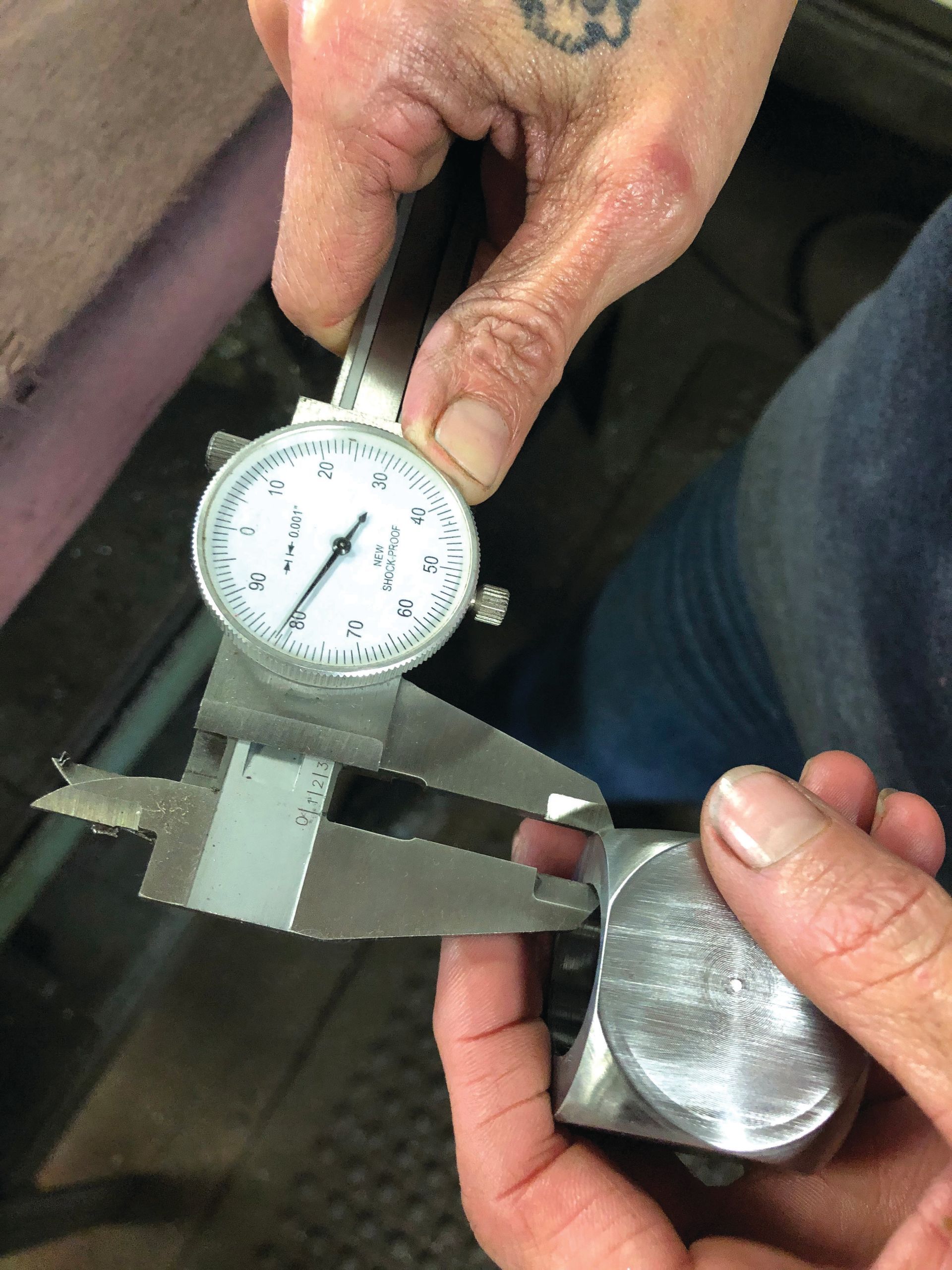 A person is measuring a piece of metal with a caliper