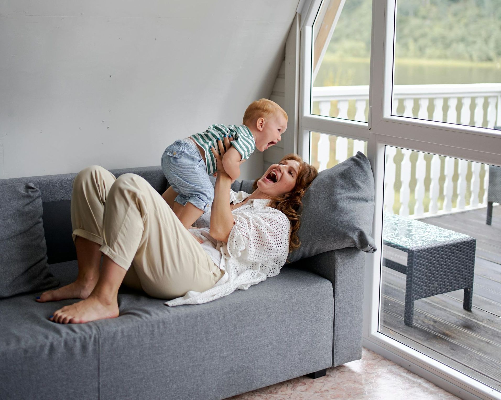 A woman is laying on a couch holding a baby in her arms.
