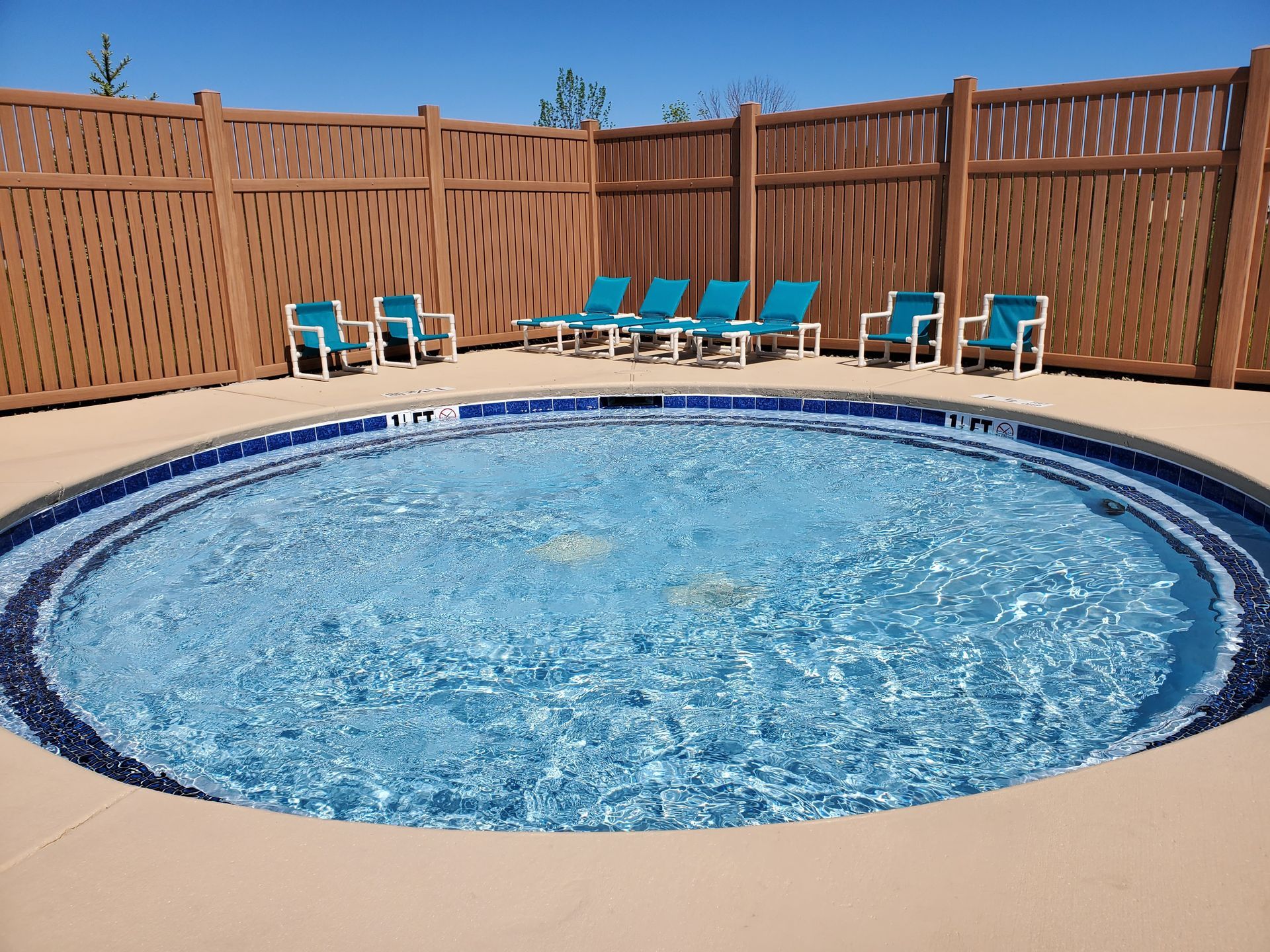 a swimming pool with a wooden fence and chairs around it