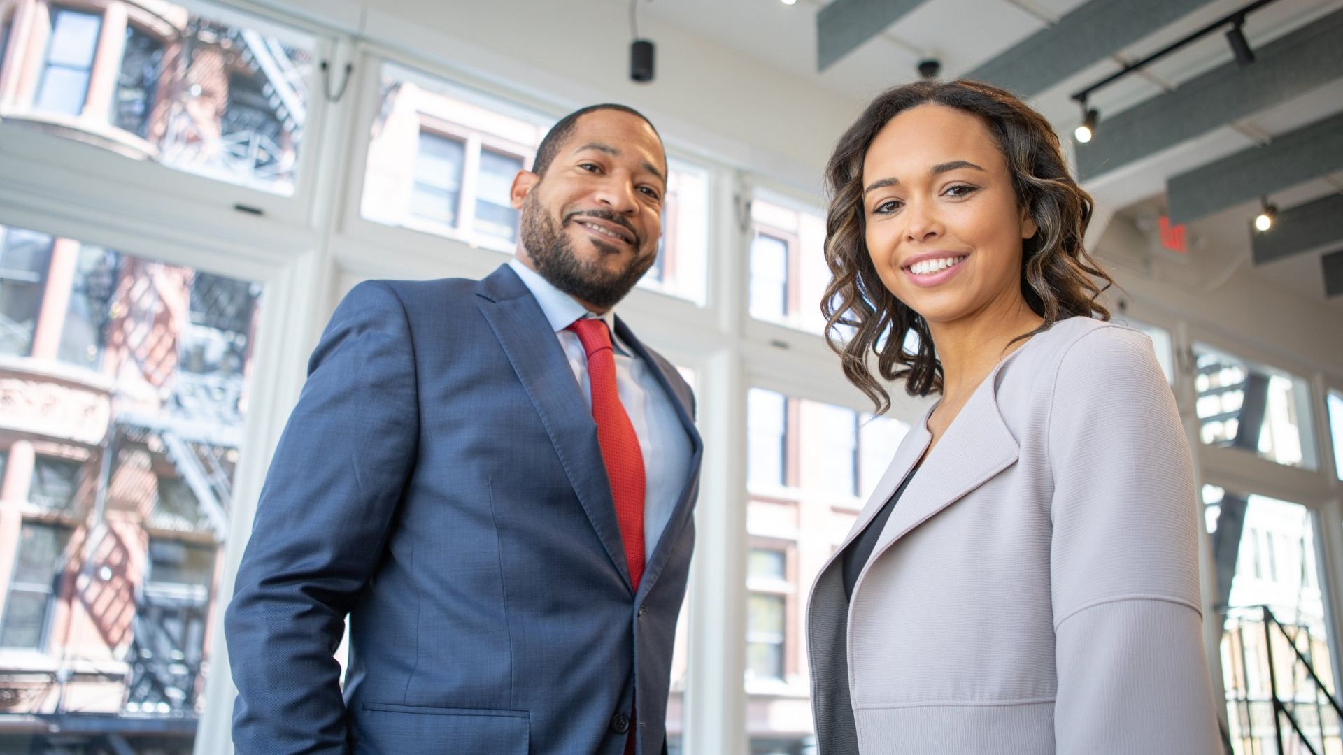 a man and a woman are standing next to each other in front of a window .