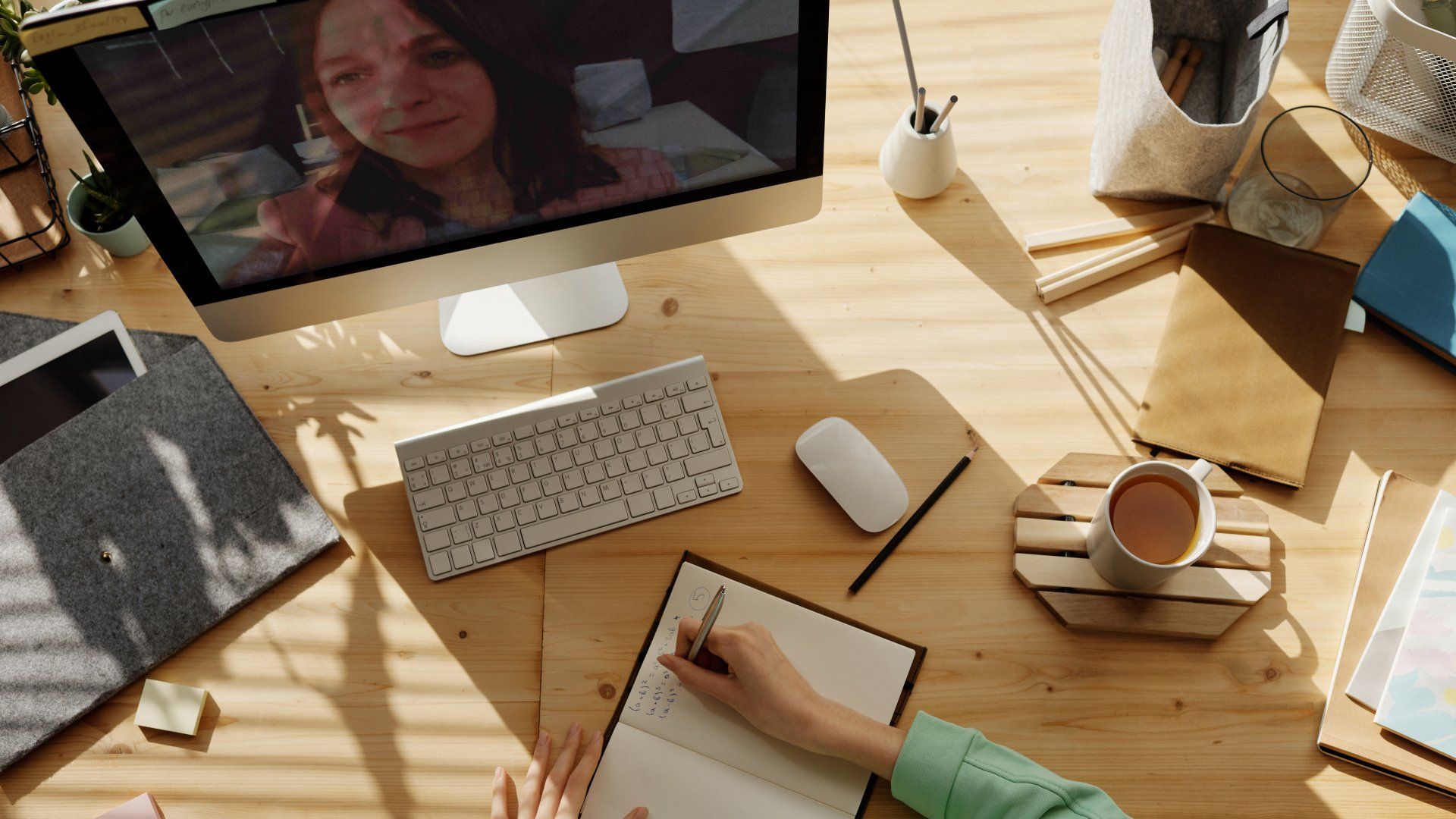 a person is sitting at a desk with a computer and a notebook .