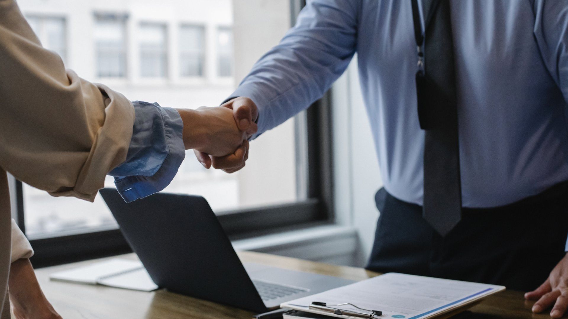 a man and a woman are shaking hands in front of a laptop .