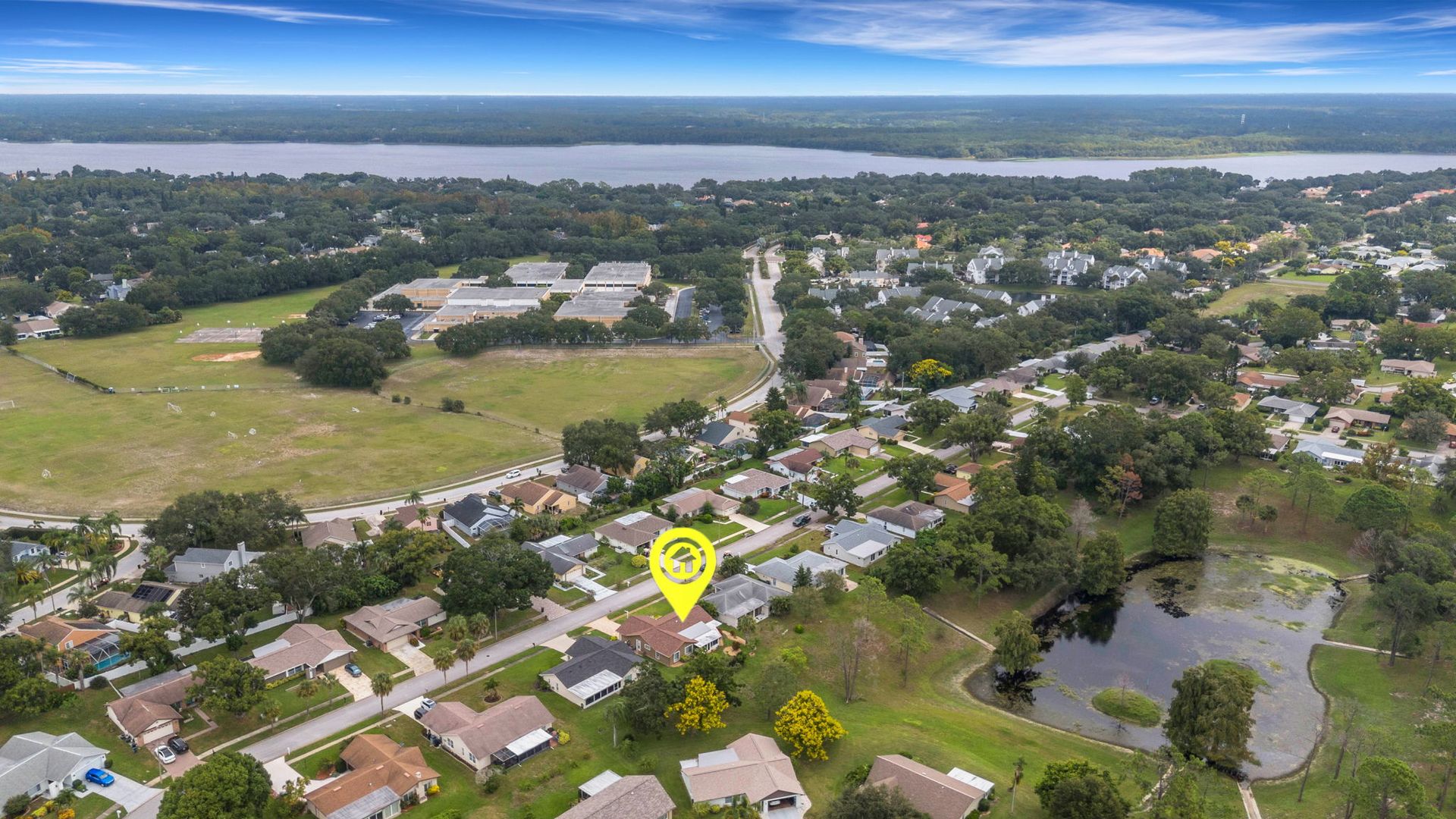 Magnifying glass over yellow house model surrounded by other colorful miniature houses on a map.
