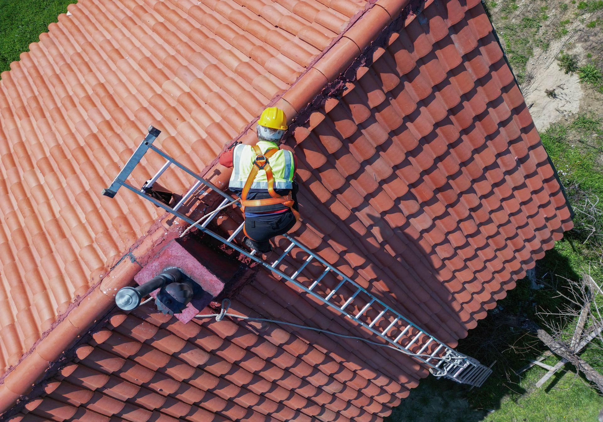 A man is standing on a ladder on the roof of a building