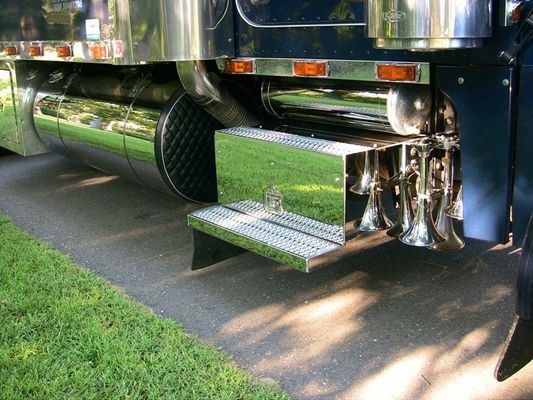 Shiny chrome semi-truck details: fuel tank, step, exhaust, and air horns.