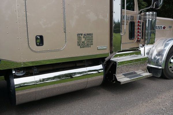 Tan and chrome semi-truck, parked outdoors. Shiny metal accents on the doors, side panels, and steps.