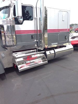 Shiny gray semi-truck with red stripes and chrome accents parked on asphalt.