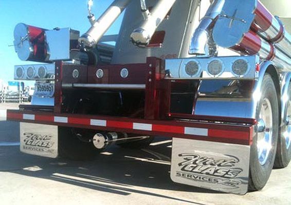 Rear view of a red and chrome tanker truck with company logo on mud flaps.