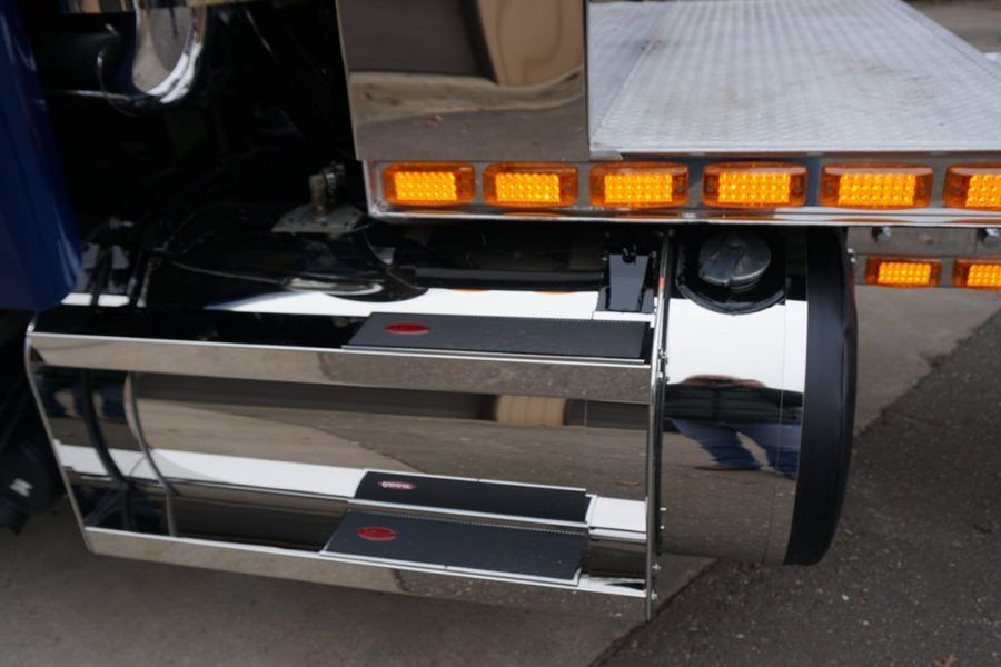 Shiny chrome side panel on a blue tow truck, with amber lights and a fuel tank visible.