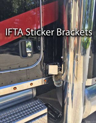 Black truck door with IFTA sticker bracket and chrome exhaust pipe.