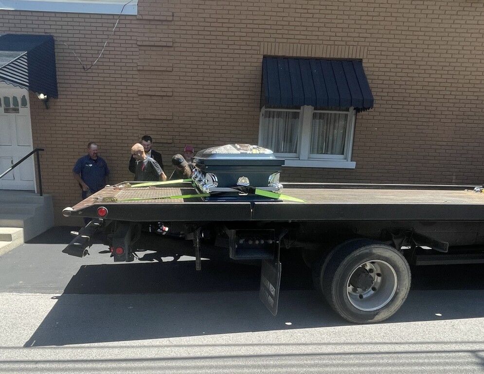 A coffin is on the back of a tow truck