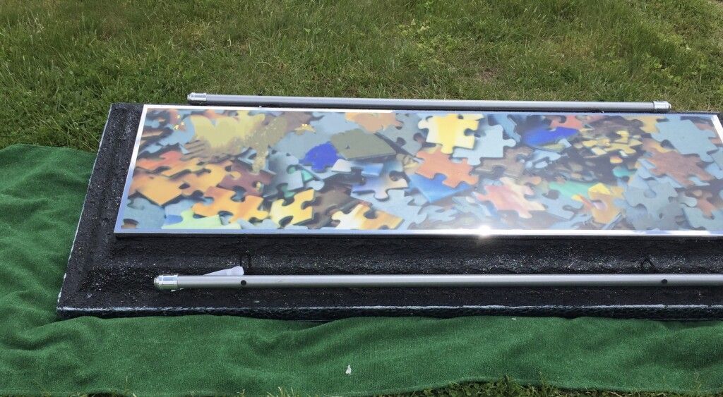 A large piece of puzzle is sitting on top of a green blanket on the grass.