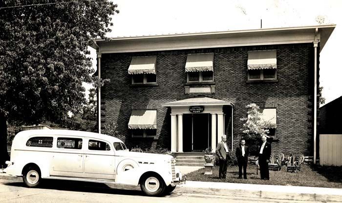 A white car is parked in front of a brick building