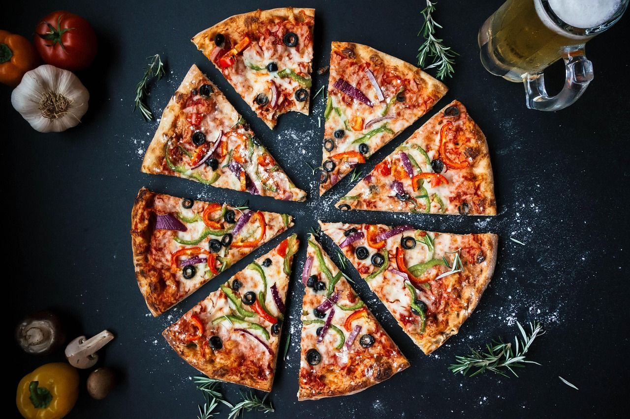 A pizza is sitting on a pizza paddle in front of a fireplace.