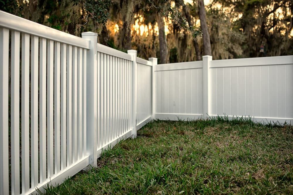 A White Vinyl Fence Surrounds A Lush Green Yard — Smiddy's Services In Tacoma, NSW