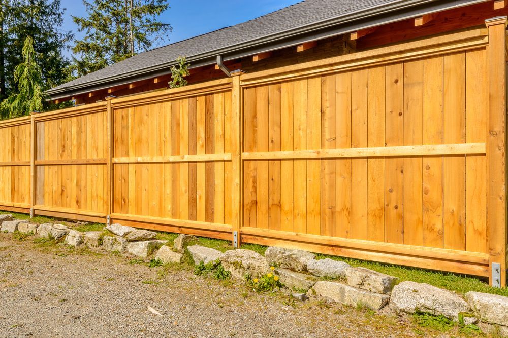 A Wooden Fence Bordering a Gravel Driveway and Green Grass — Smiddy's Services In Toukley, NSW