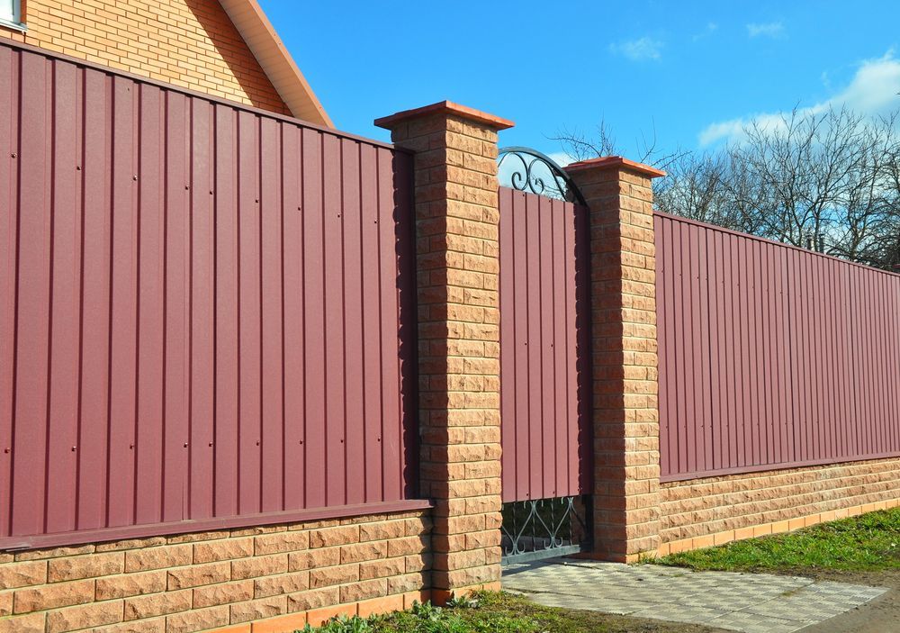 A Red Corrugated Metal Fence With Brick Pillars — Smiddy's Services In Morisset, NSW