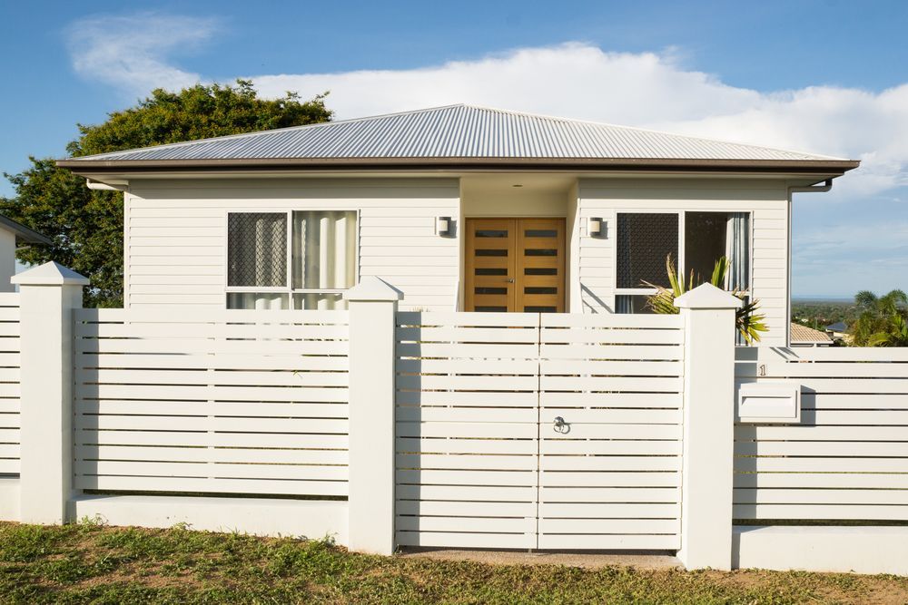 A White House With a Slatted Fence and Gate — Smiddy's Services In Bateau Bay, NSW