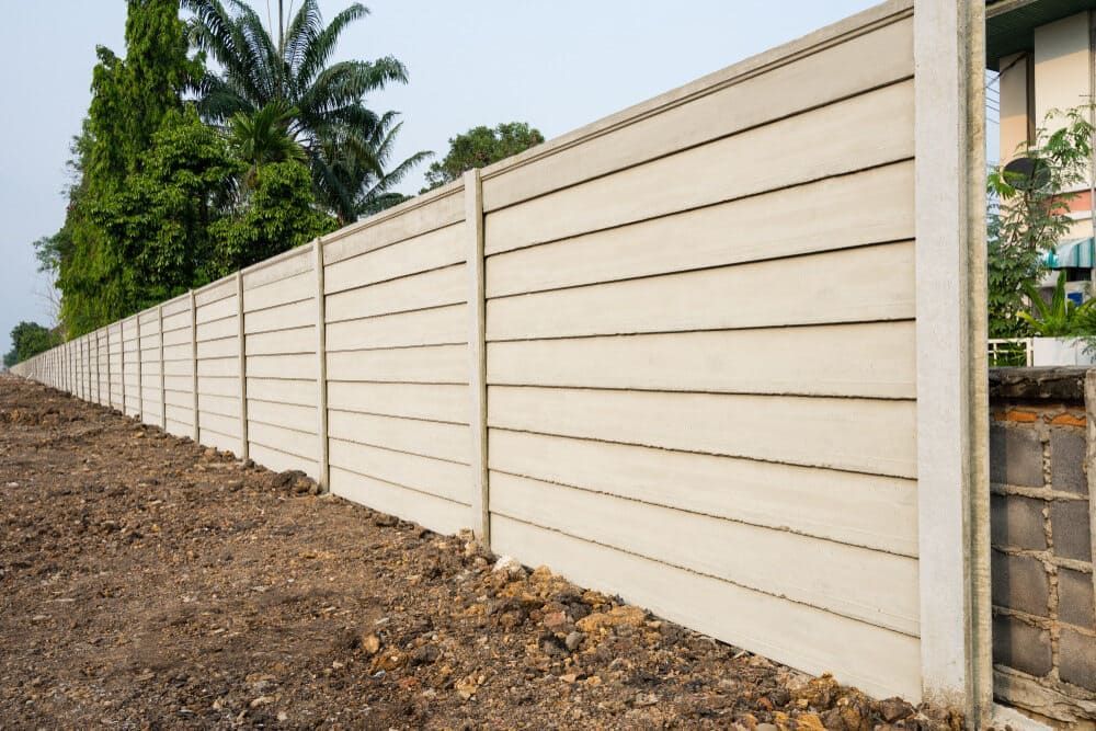 A Concrete Fence Is Sitting On Top Of A Dirt Field — Smiddy's Services In Tacoma, NSW