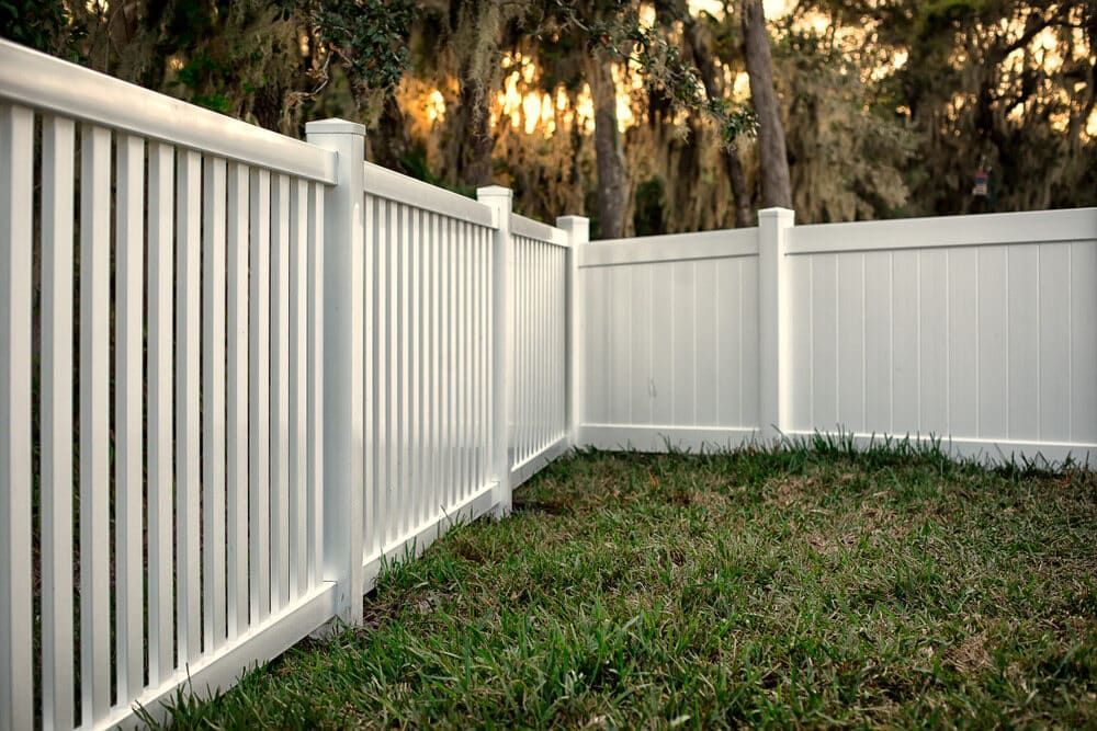 A White Vinyl Fence Surrounds A Lush Green Yard — Smiddy's Services In Central Coast, NSW