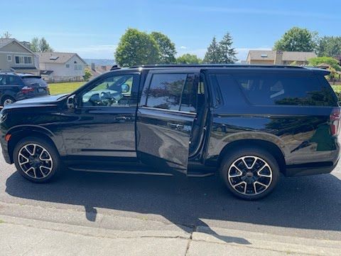 A black suv is parked on the side of the road with its doors open.